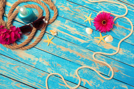 Summer vacation concept of ropes, sunglasses and pink blossoms on blue wooden backgroundの写真素材