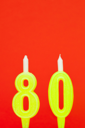 Colorful burning birthday candle  on red backgroundの写真素材