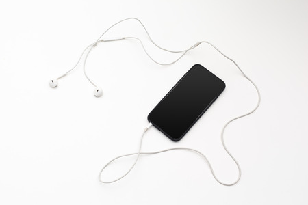 Creative flat lay photo of workspace desk with earphones and mobile phone