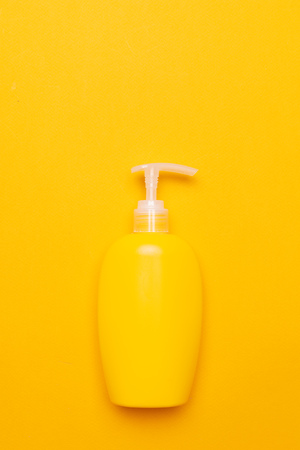 Yellow plastic bottle of sunscreen protection cosmetic lotion on bright backgroundの写真素材