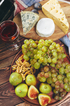 Grape, cheese, figs and honey with wine on wooden tableの写真素材