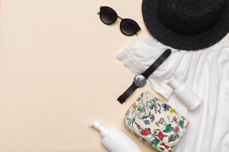 Composition of white dress, black straw hat, sunglasses, handbag and other accessories on pastel...