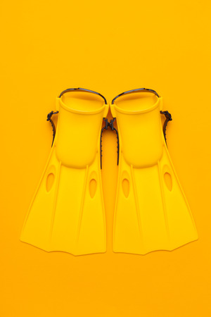 Yellow swimming flippers on colored background