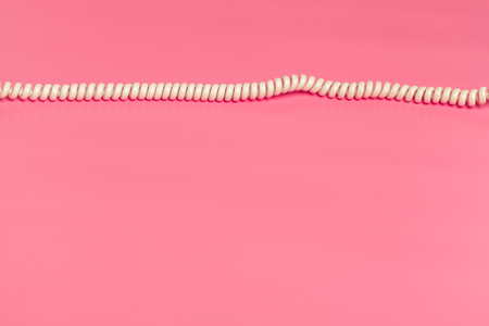 White telephone cord on bright pink background top viewの写真素材
