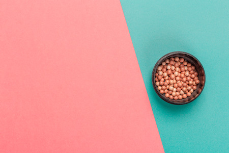 Cosmetic powder balls on color block background top view