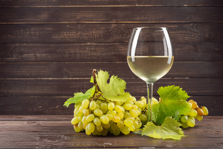 wine glass and bunch of grapes on wooden tableの写真素材