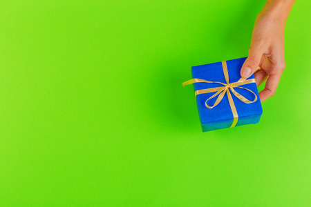 Woman holding gift box on color backgroundの写真素材