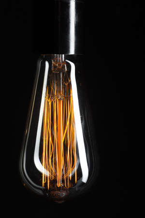 A classic Edison light bulb on dark background with space for text