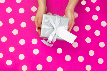 Woman hands holding gift box on pink backgroundの写真素材