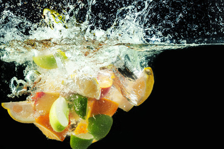 many fruits splashes into waterの写真素材