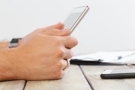 hands of a man holding tablet device over a wooden workspace tableの写真素材