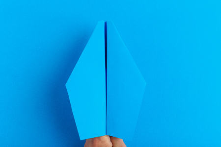 Paper plane on bright background holding in human hand. Travel and tourism conceptの写真素材