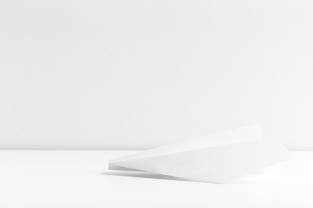 Flat lay of white paper plane on white color backgroundの写真素材