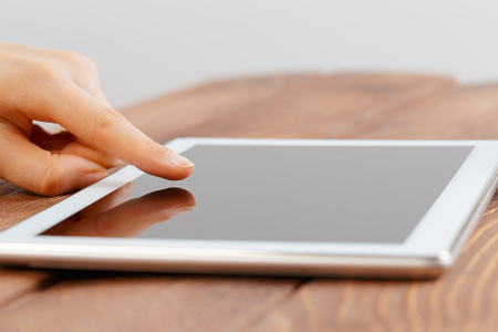 woman holding blank tablet device over a wooden workspace table