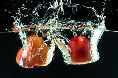 Peach dropped into water with bubblesの写真素材