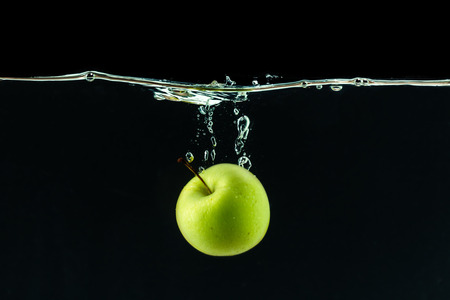 Green apple under waterの写真素材