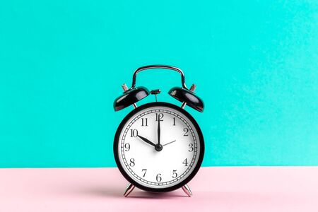 black vintage alarm clock on color background. Creative Photo