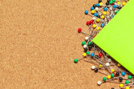 Stack of sticky notes surrounded with a bunch of colorful push pins