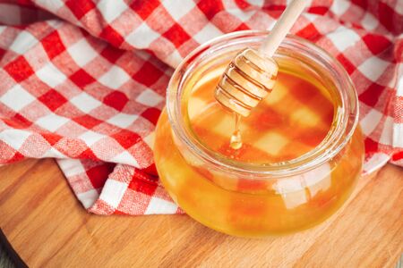 Honey background. Sweet honey in glass jar on wooden background. creative photo.の写真素材