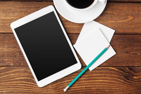 Digital tablet computer and cup of coffee on wooden desk. Creative photo.の写真素材