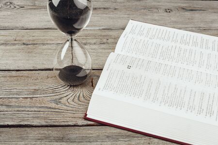 Hourglass and open bible. creative photo.