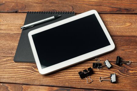 Tablet with notepad on wooden background. creative photo.の写真素材