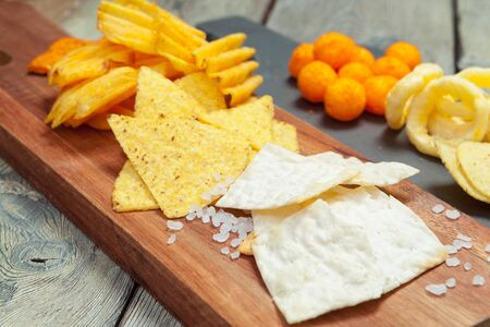 Mix of snacks : pretzels , crackers , chips and nachos on the table. Creative photo.