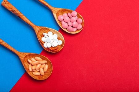 Multicolored pills in a spoon on a color backgroundの写真素材