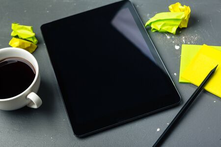 Digital tablet computer and cup of coffee on wooden desk. Creative photo.の写真素材