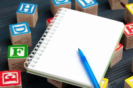 Notepad on wooden table and wood alphabet blocksの写真素材