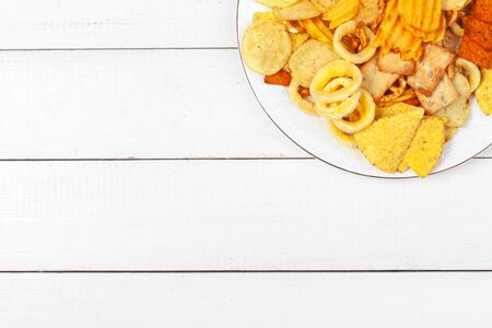 Mix of snacks : pretzels , crackers , chips and nachos on the table. Creative photo.