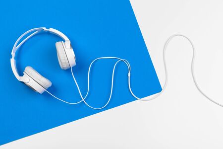 Stylish headphones on blue and white color background, top view. Creative photo.の写真素材