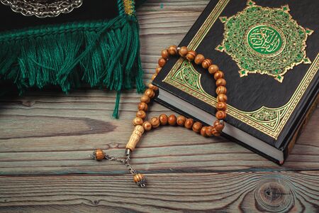 Holy Quran with beads over wooden background