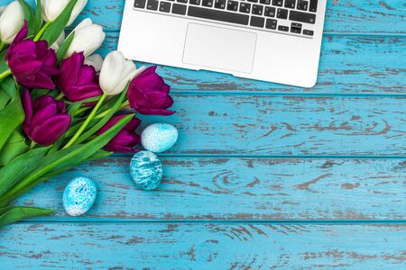 Easter eggs, mockup laptop and bouquet of tulips. creative photo.の写真素材