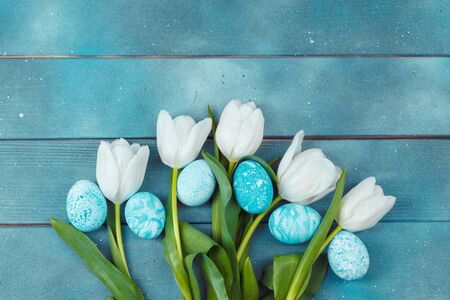 Easter eggs with tulips on blue wooden backgroundの写真素材