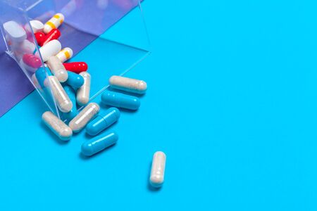 set of multi-colored tablets and capsules on a blue background