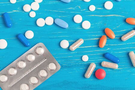Many different pills on dark blue wooden background. creative photo.