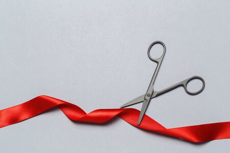 Grand Opening illustrated with scissors and a red ribbon on a gray background. creative photo.の写真素材