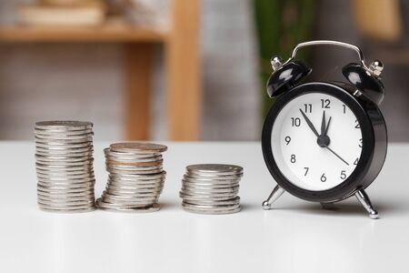 Alarm clock and money coins on the table. creative photo.
