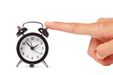 Female hand holding alarm clock on white background. creative photo.の写真素材