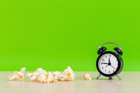 Popcorn and small alarm clock on pastel green background minimal creative concept.の写真素材