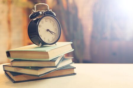 alarm clock near books on the table. creative photo.