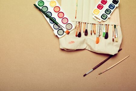 Set of professional watercolor artist brushes in a hand made roll case and watercolor paints close up. creative photo.の写真素材