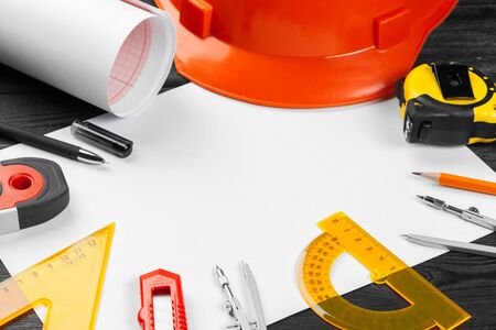 Close up orange hardhat and variety of repair tools with copy space in the middle over wooden...