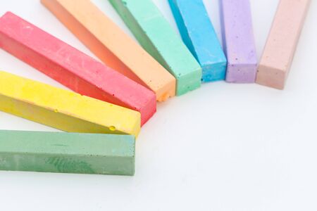 Colored chalks over a white background close up creative photo.