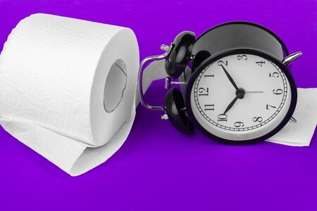 Alarm clock with toilet paper on a purple backgroundの写真素材