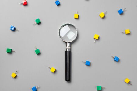 magnifying glass with paper clips on grey background.minimalism concept creative photo.の写真素材