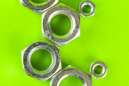 Tools. Nuts on green background close up creative photo.
