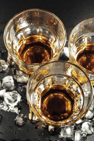 Whiskey and ice on rustic wood background creative photo.