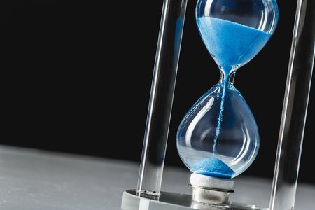 Hourglass on dark background creative photo.